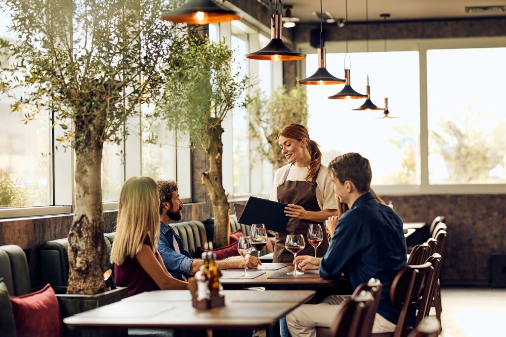 Server taking an order from guests in a restaurant dining room
