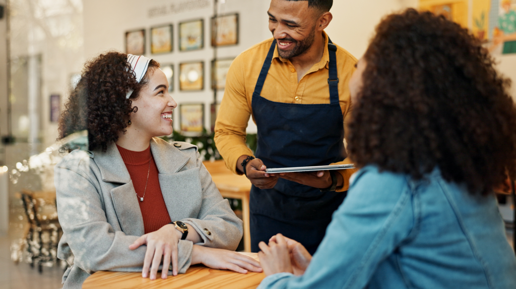 Restaurant server interacting with customers representing consumer behavior in the food industry