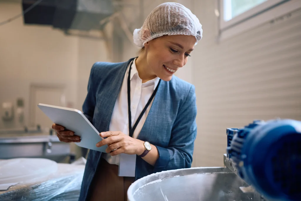 Food manufacturing professional reviewing production data on a tablet in a processing facility